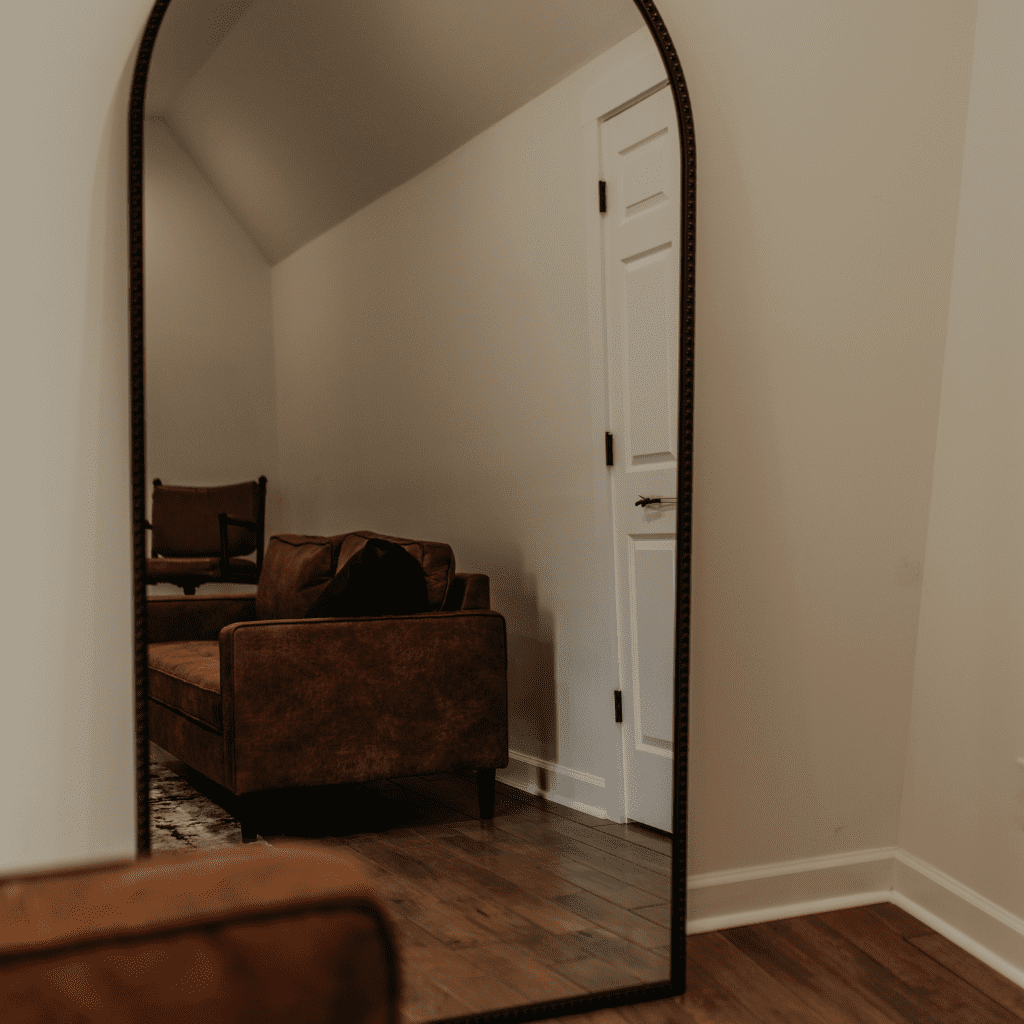 Full-length mirror reflecting leather sofa in groom’s gallery at Grahams Estate Nashville TN