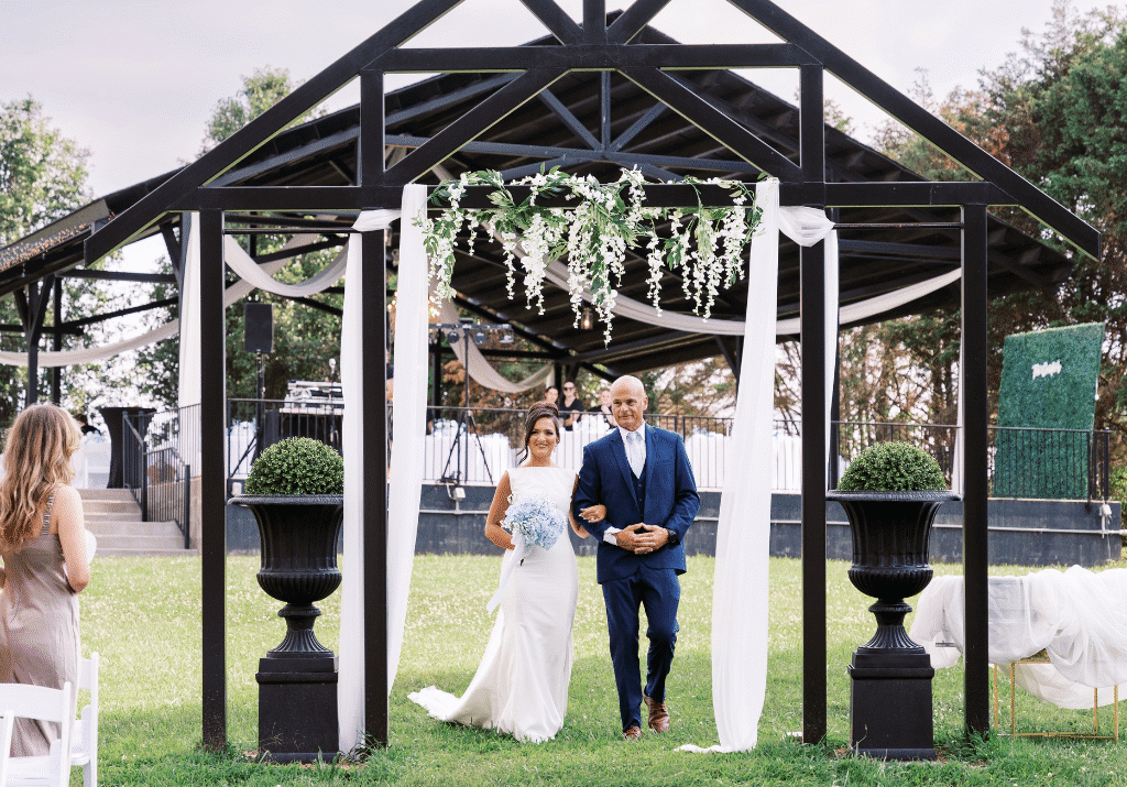 Bride walking down the aisle under floral archway at Grahams Estate wedding pavilion in Gallatin Tennessee