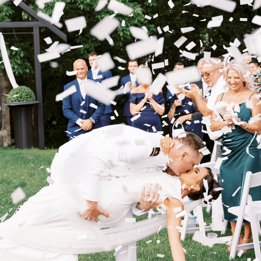 Bride and groom kissing surrounded by confetti and streamers