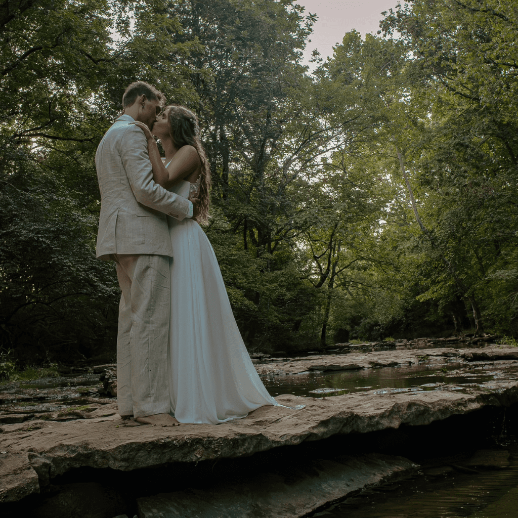 Bride and groom kissing beside creek at Grahams Estate Gallatin