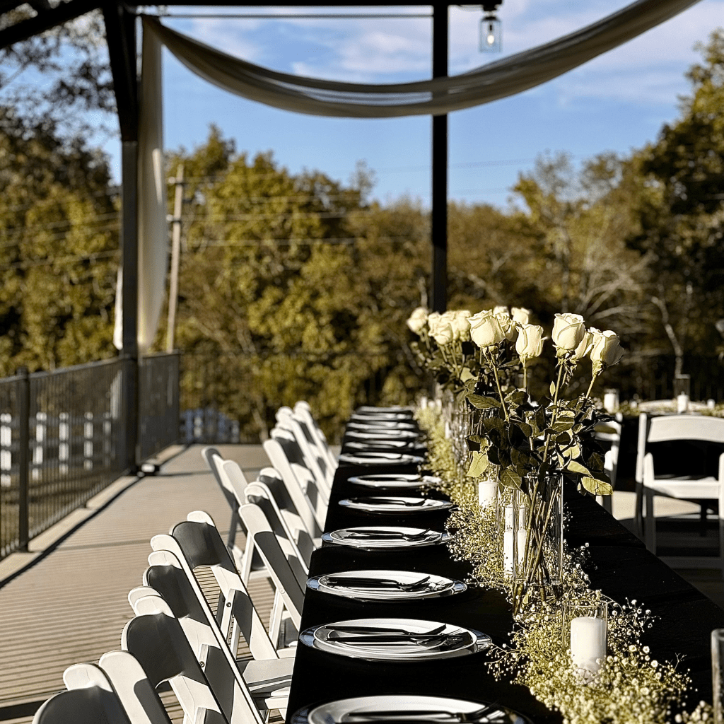 Long black table with white roses and candles set for outdoor wedding reception at Grahams Estate Gallatin TN