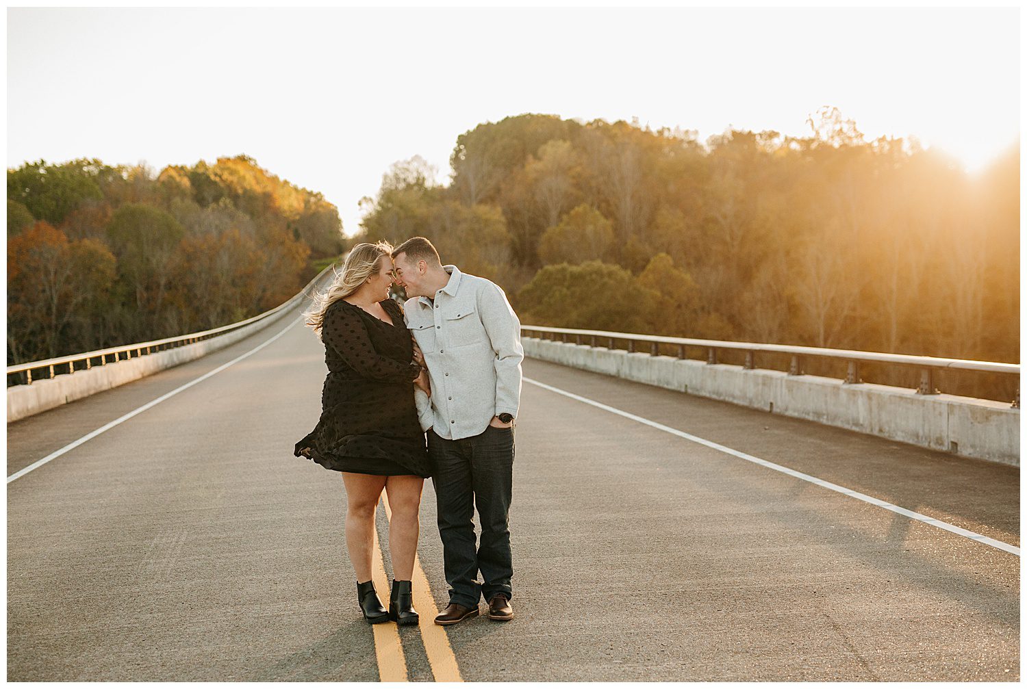Couple standing near Natchez Trace Parkway Bridge with rolling hills behind them