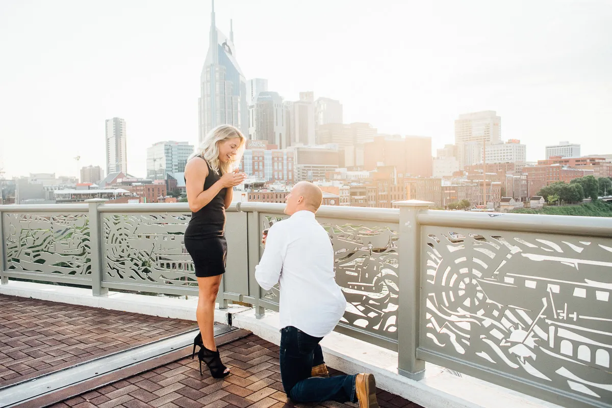 Couple celebrating an engagement with the Nashville skyline in the background at sunset