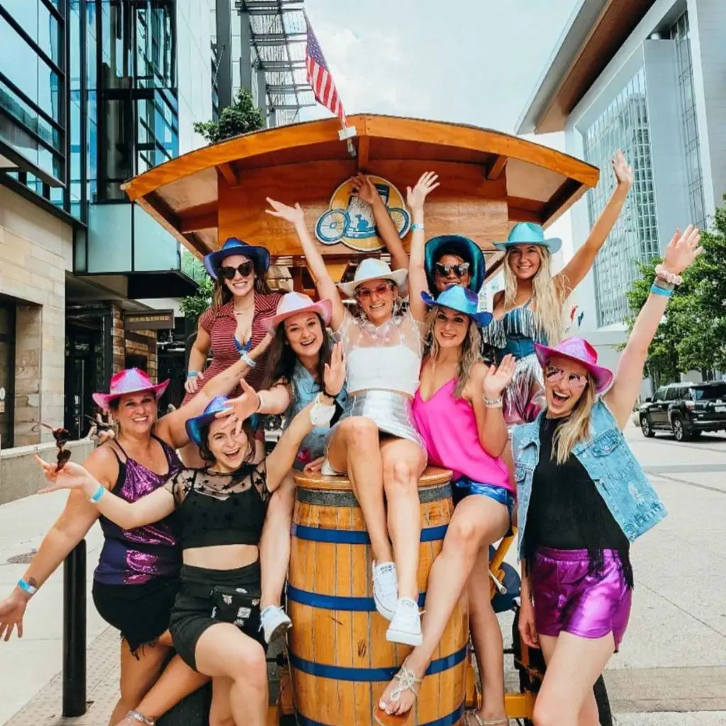 Bride and friends cheering on a Nashville pedal tavern during a bachelorette party
