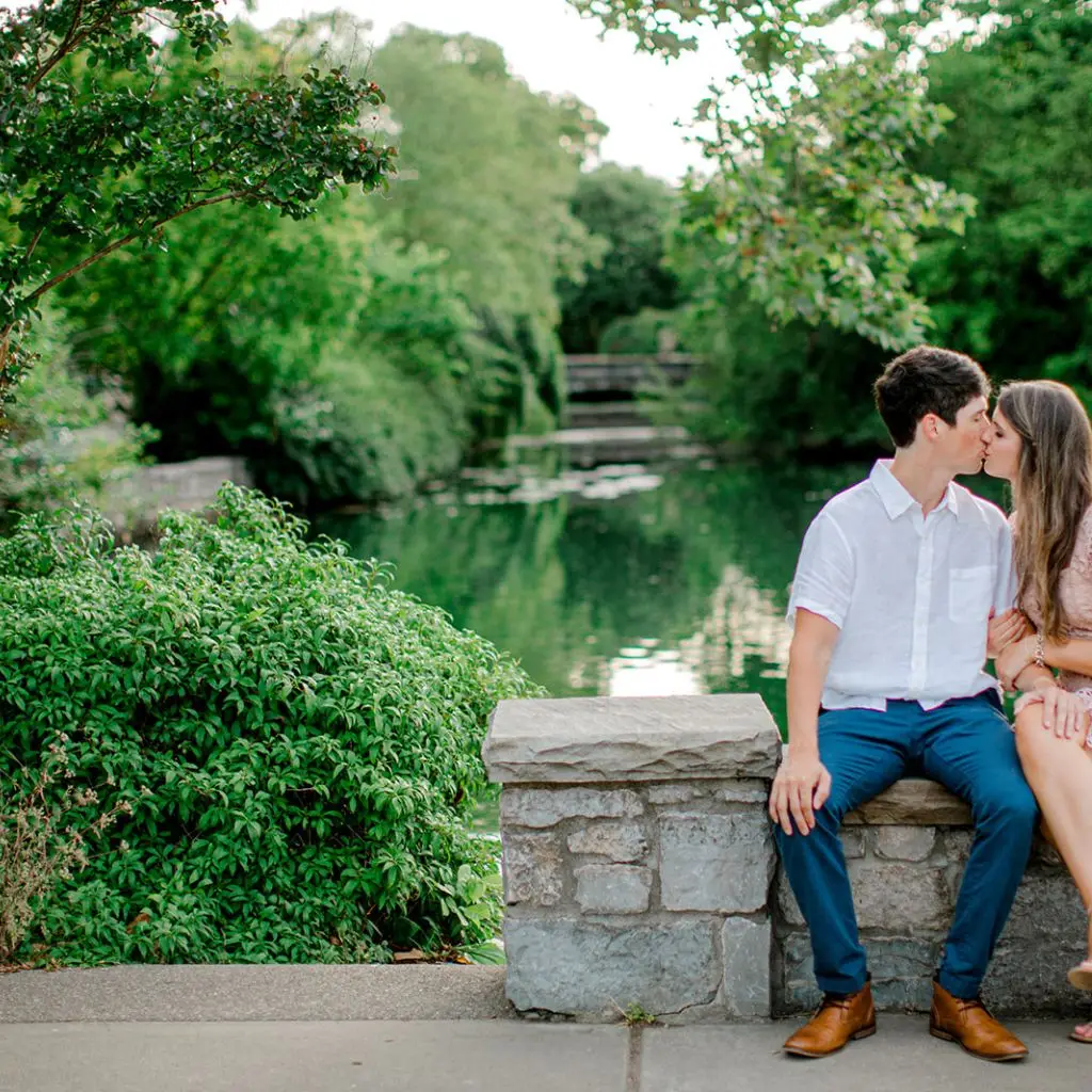 Engaged couple walking together along the greenery at Centennial Park in Nashville.