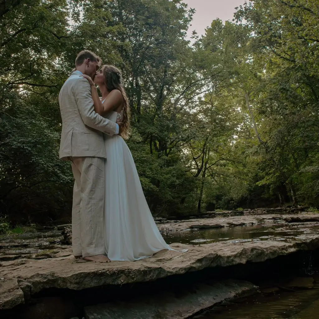 Bride and groom sharing a quiet moment on a creekside rock at a wedding venue in Gallatin TN.