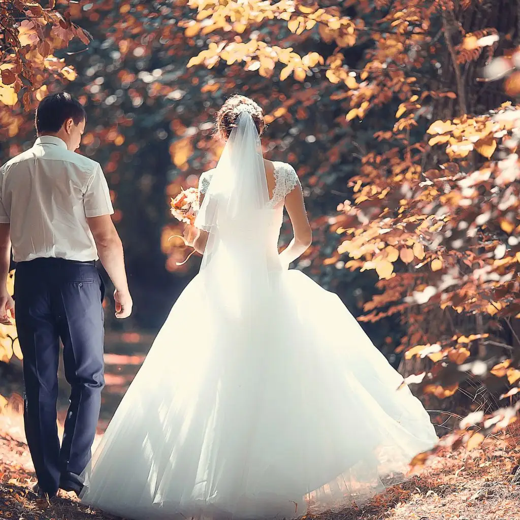 “Bride and groom walking along a forest path surrounded by golden fall leaves in Gallatin, TN.