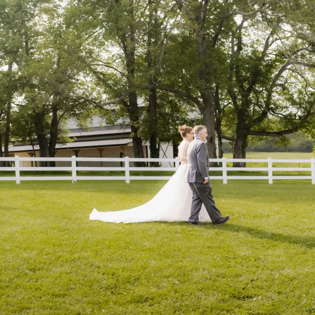 Bride walking across the lawn at Grahams Estate with the venue’s white fencing and trees in the background in Gallatin Tennessee