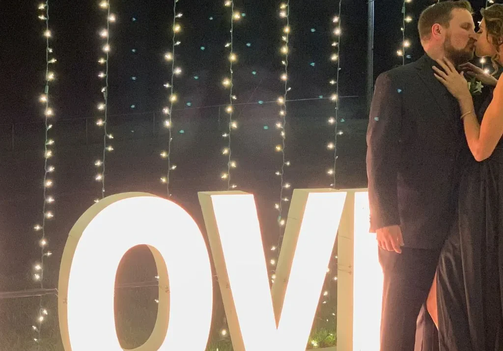 A couple sharing a romantic nighttime moment beside the glowing LOVE sign at Grahams Estate, highlighting the venue’s enchanting atmosphere and decorative lighting options for weddings in Gallatin, Tennessee.