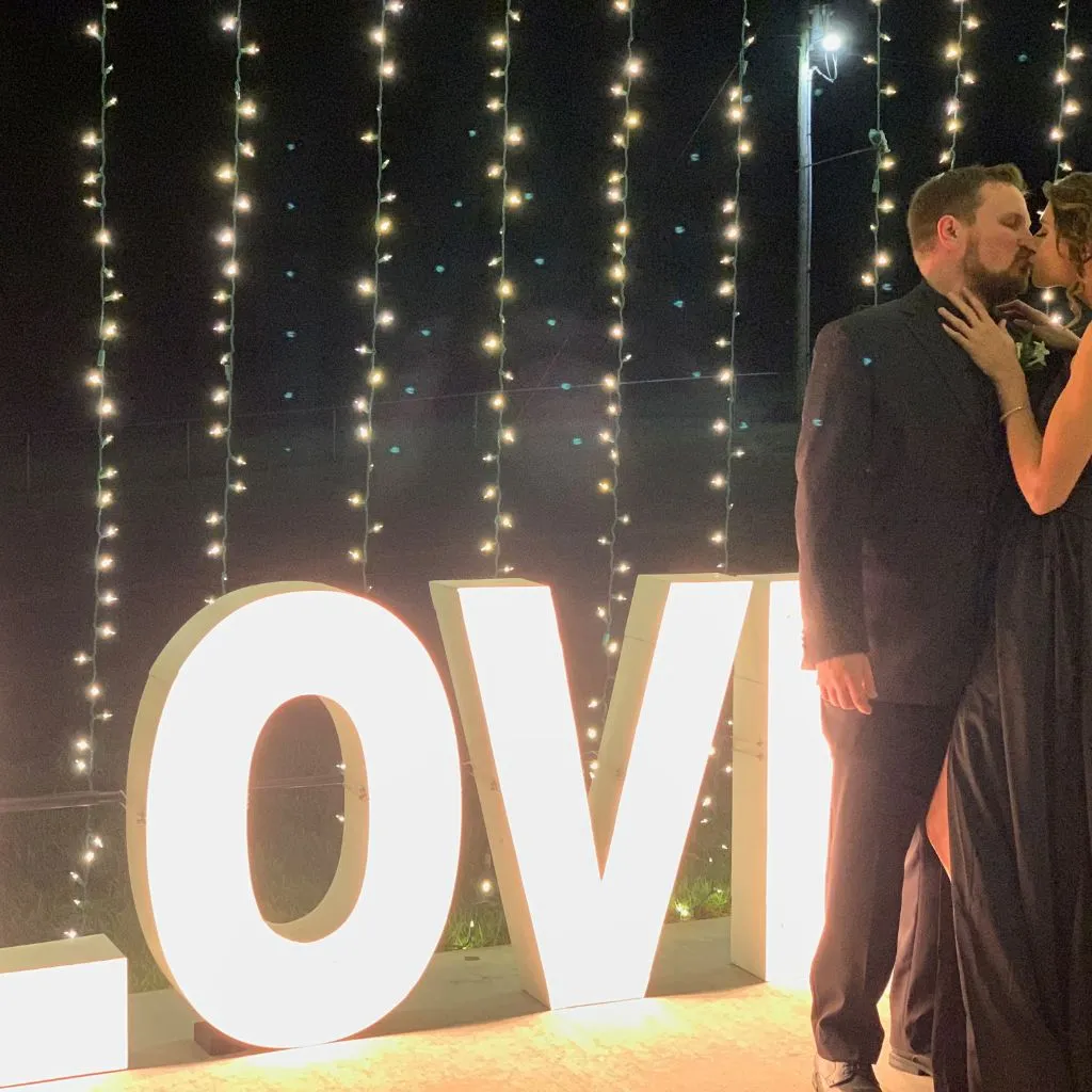 A couple sharing a romantic nighttime moment beside the glowing LOVE sign at Grahams Estate, highlighting the venue’s enchanting atmosphere and decorative lighting options for weddings in Gallatin, Tennessee.