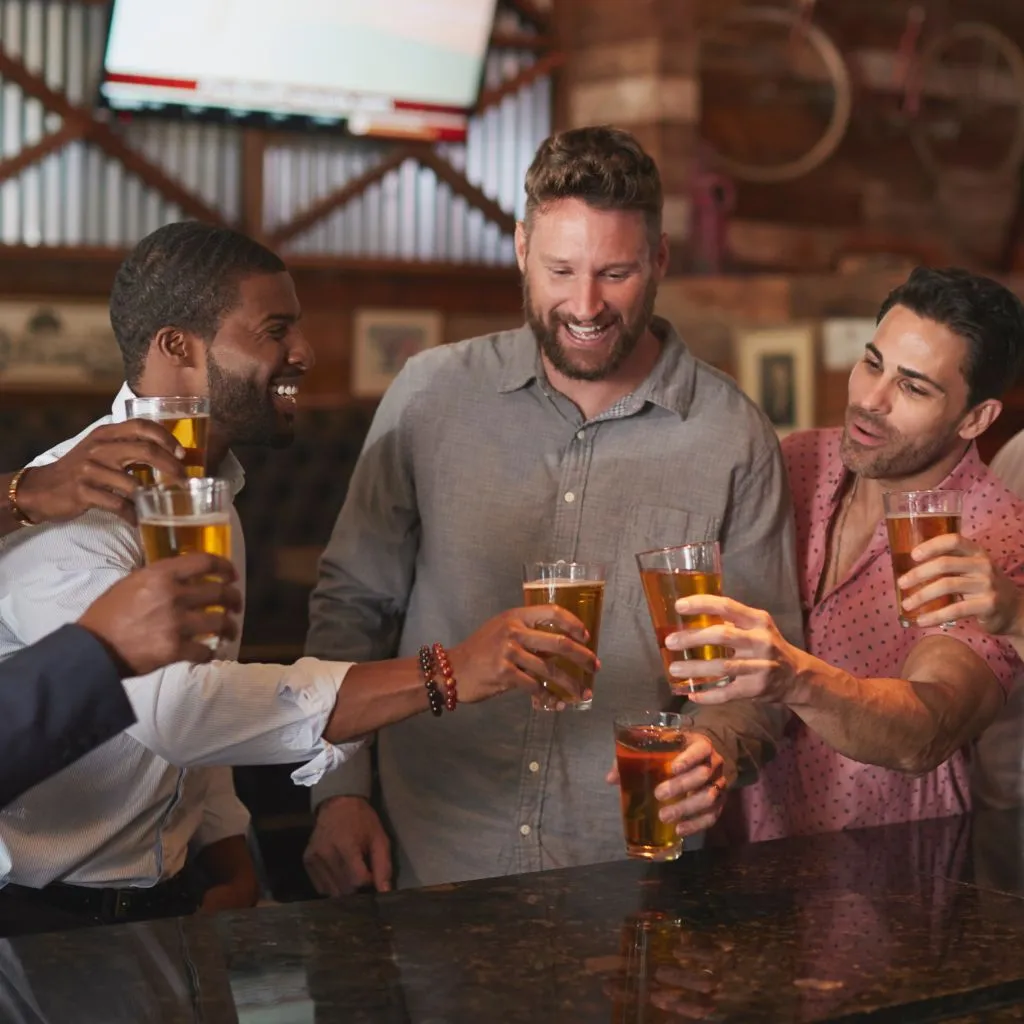 Groom and groomsmen toasting at a Nashville bar while planning a bachelor weekend