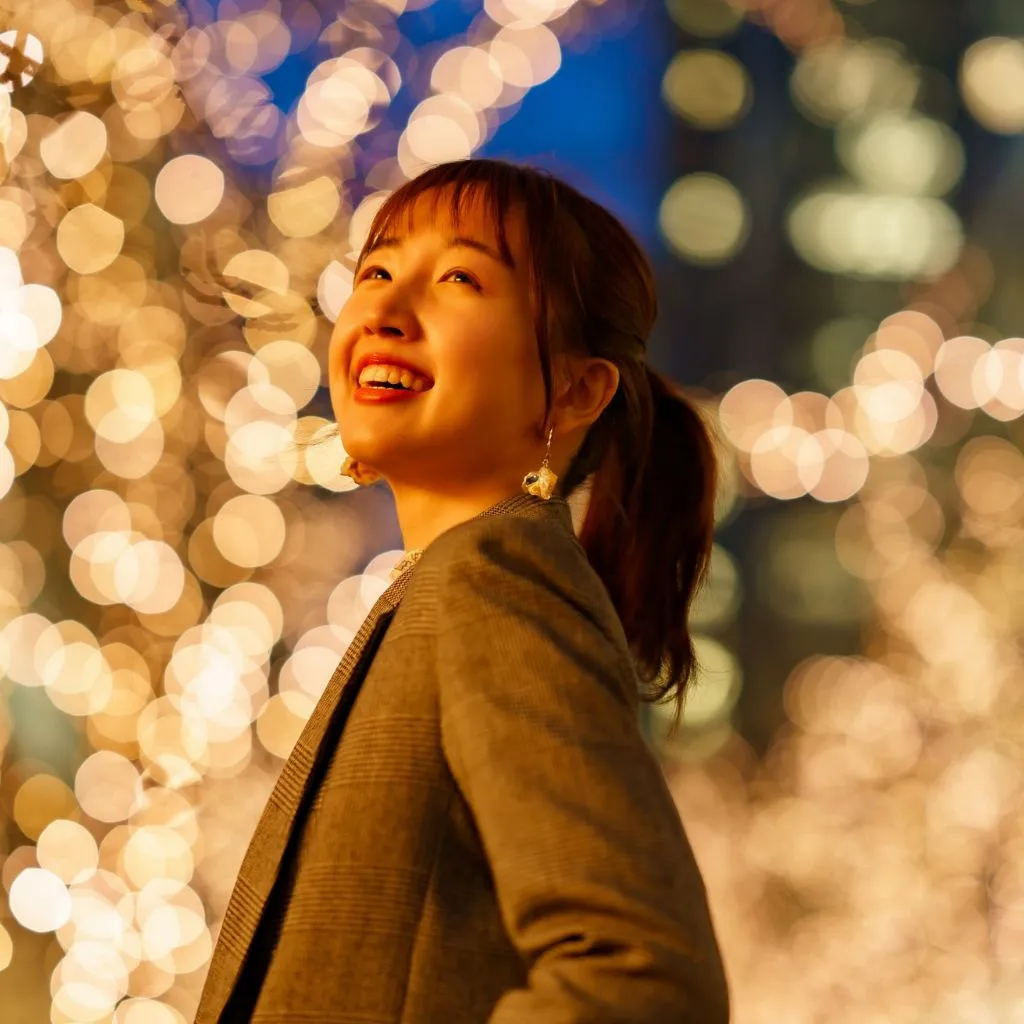 Woman smiling under sparkling holiday lights in downtown Nashville