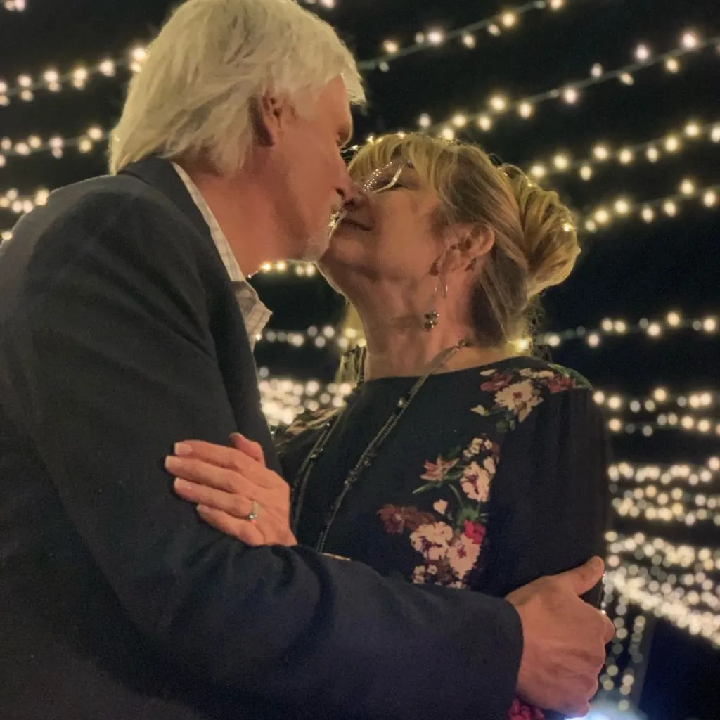Couple sharing a kiss beneath glowing string lights during an evening celebration at Grahams Estate in Gallatin, Tennessee.