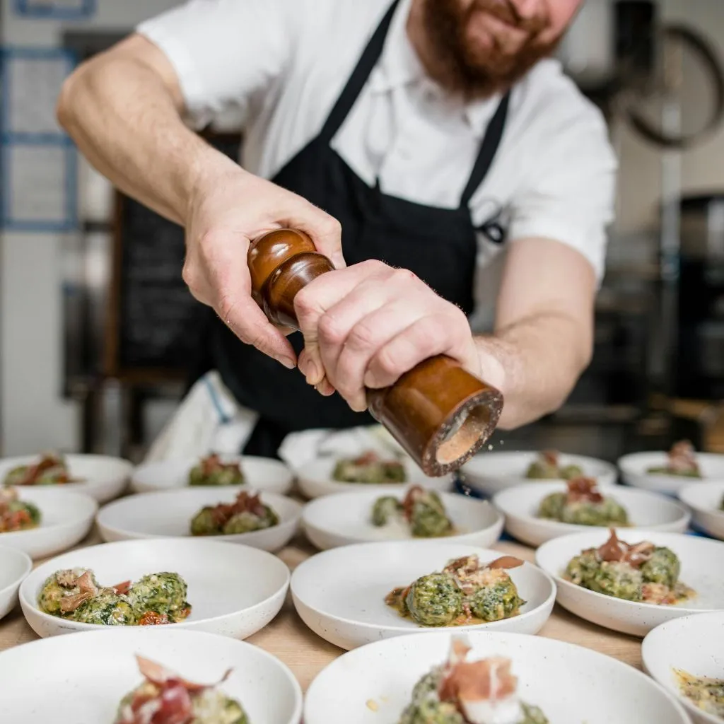 Chef seasoning gourmet dishes for a downtown Nashville rehearsal dinner