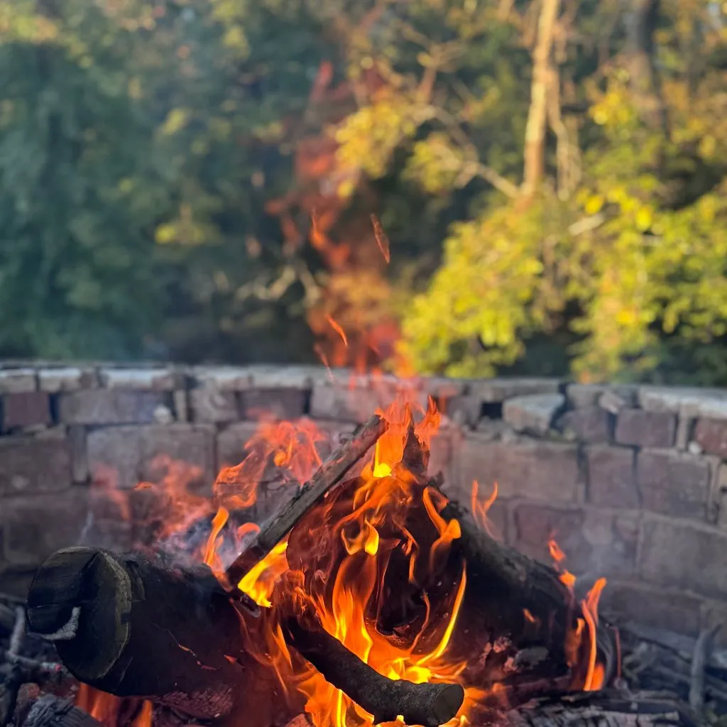 Fire pit with glowing wood and flames during an evening gathering at a wedding venue in Gallatin TN.