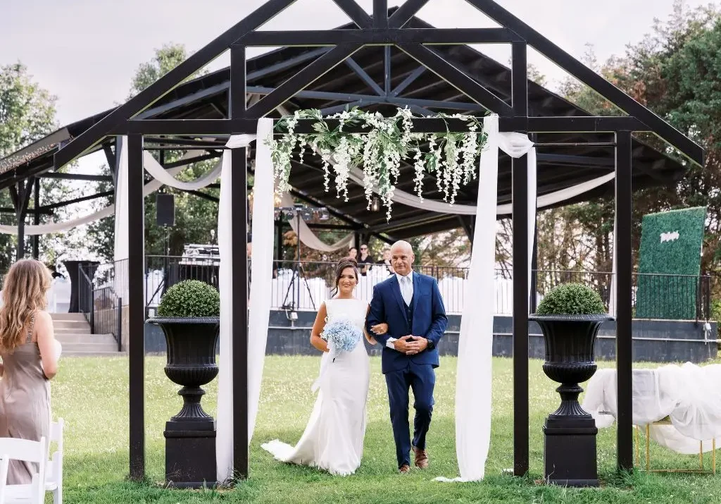 Bride walking down the aisle under a decorated ceremony arch at a wedding venue in Gallatin TN.