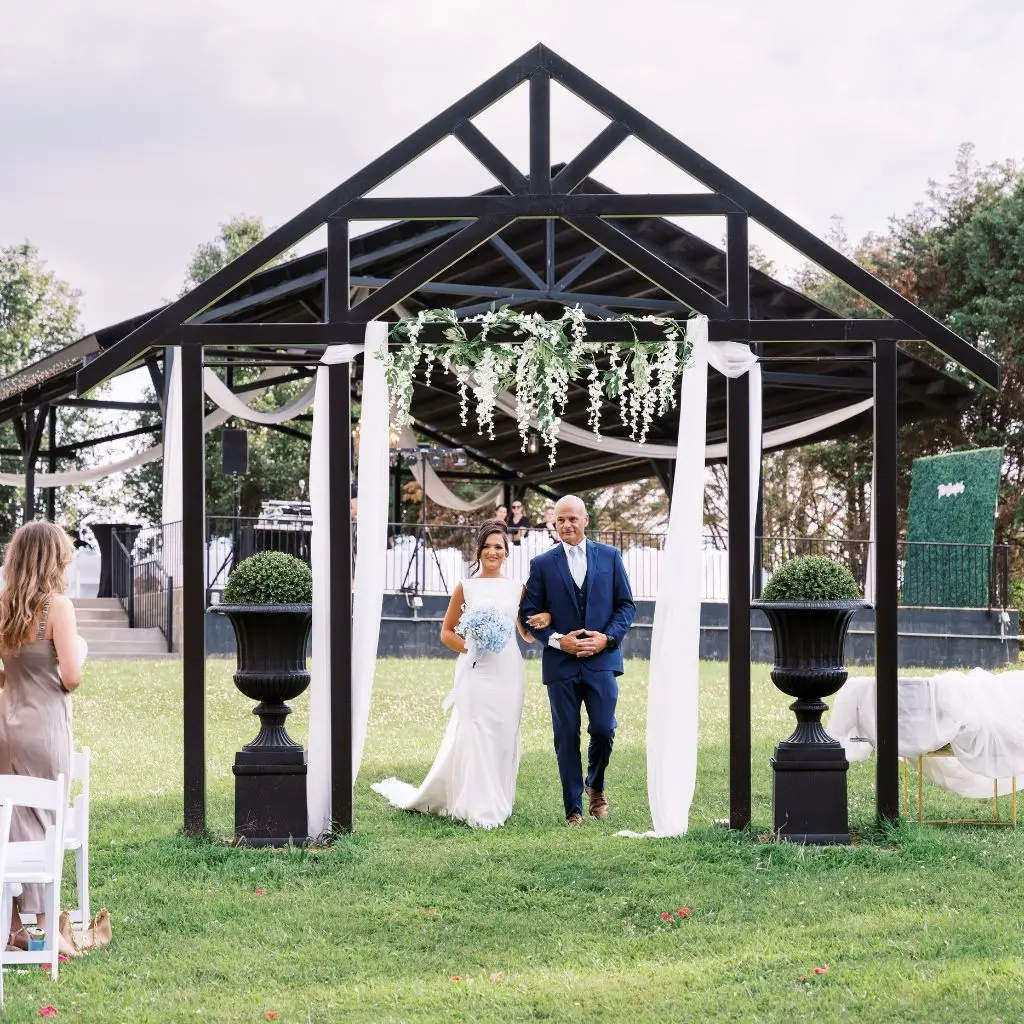 Bride walking down the aisle under a decorated ceremony arch at a wedding venue in Gallatin TN.