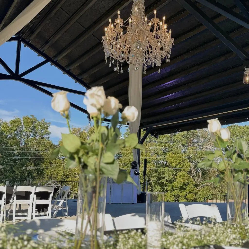 Chandelier hanging above an outdoor reception pavilion with floral centerpieces at a wedding venue in Gallatin TN.