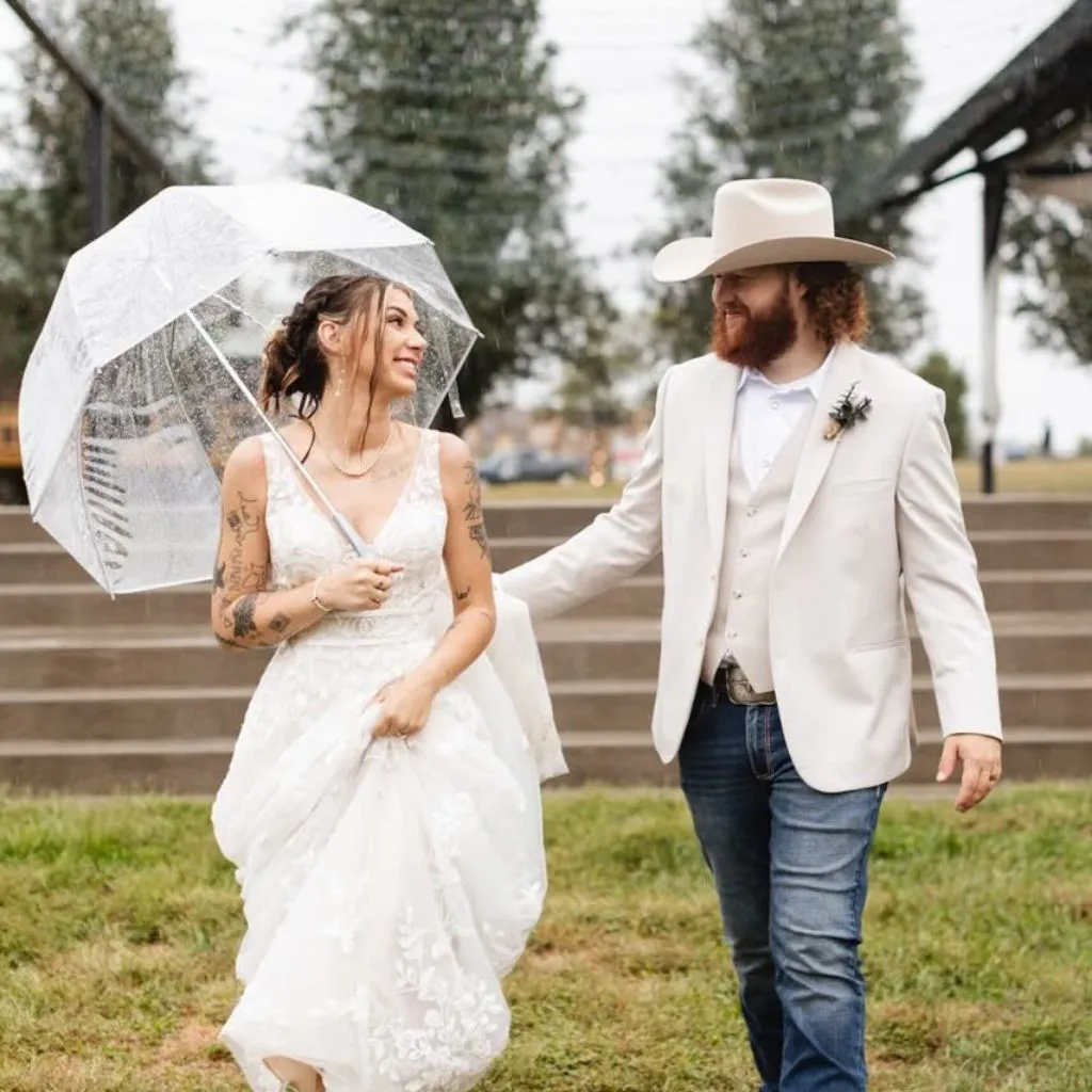 Bride and groom walking under an umbrella on a rainy day at a wedding venue in Gallatin TN.