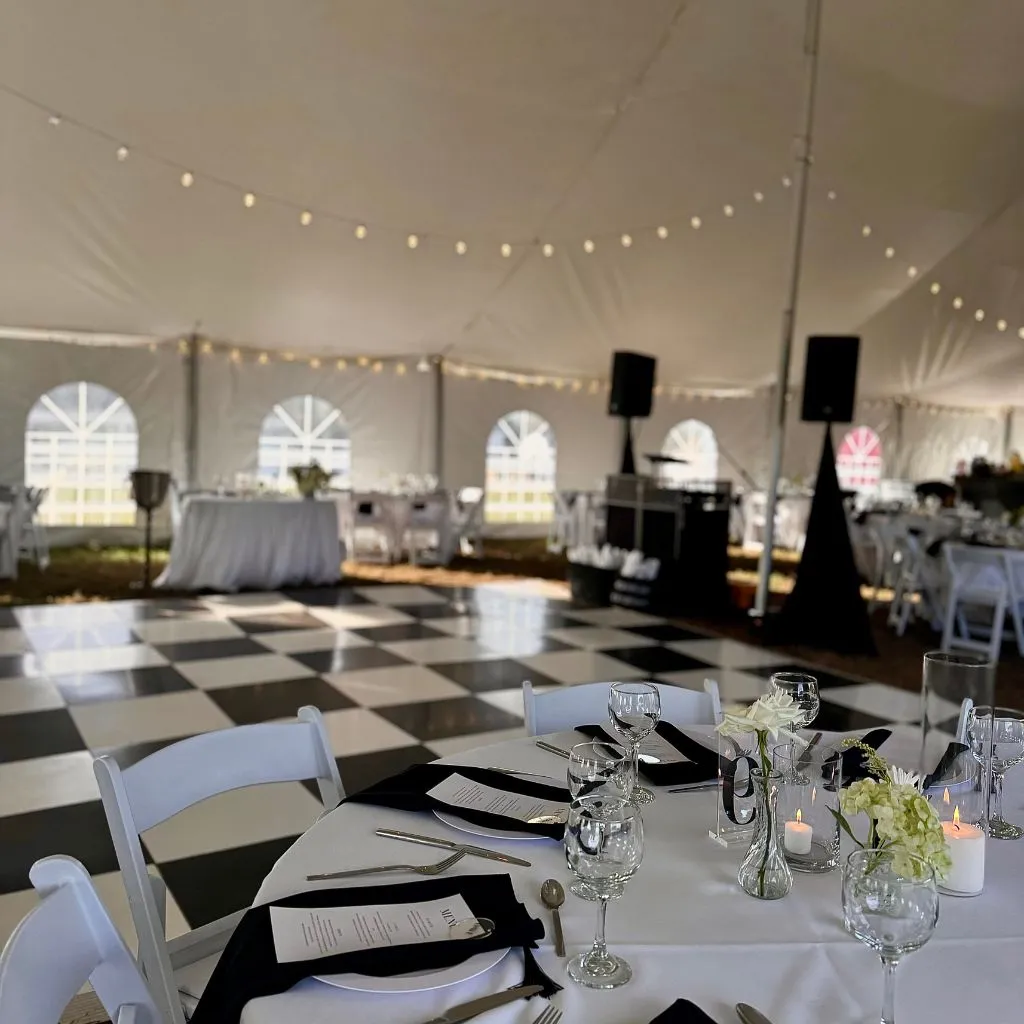 Elegant tented reception with decorated tables, candles, and a black and white dance floor at a wedding venue in Gallatin TN.
